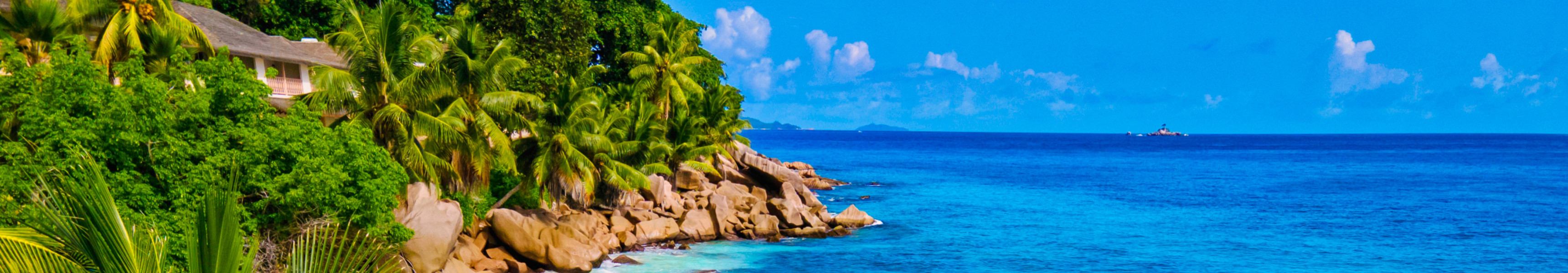 Ein Paar spaziert Hand in Hand am wei&szlig;en Sandstrand von Anse Intendance auf den Seychellen, umgeben von t&uuml;rkisfarbenem Wasser, Palmen und beeindruckenden Granitfelsen.