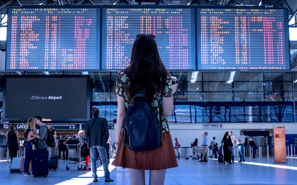 Frau am Flughafen überprüft Abflugzeiten